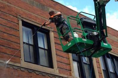 Commercial Pressure Washing Company in Waukesha - Pressure washing a brick building from a bucket truck with a hand held pressure washer.